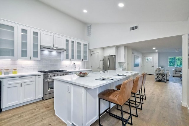 kitchen featuring a center island with sink, appliances with stainless steel finishes, white cabinets, and a breakfast bar