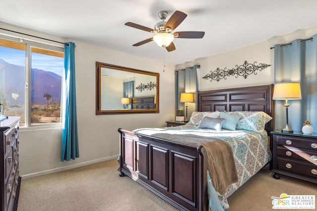 carpeted bedroom with ceiling fan, a mountain view, and multiple windows