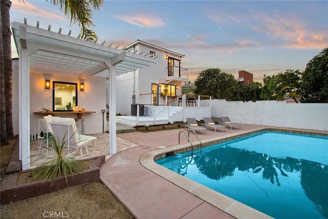 pool at dusk featuring a pergola and a patio area