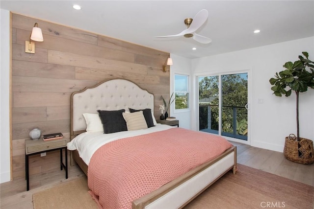 bedroom with ceiling fan, access to exterior, wood walls, and light wood-type flooring