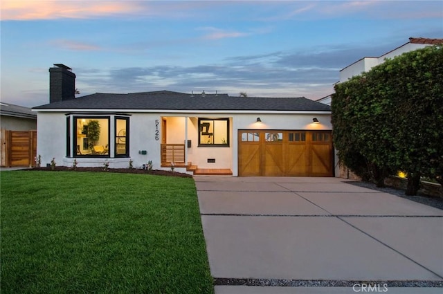 view of front facade featuring a garage, driveway, a chimney, a front lawn, and stucco siding