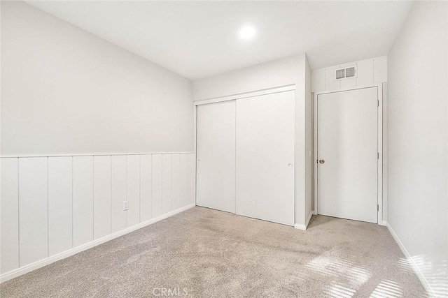 unfurnished bedroom with a closet and light colored carpet