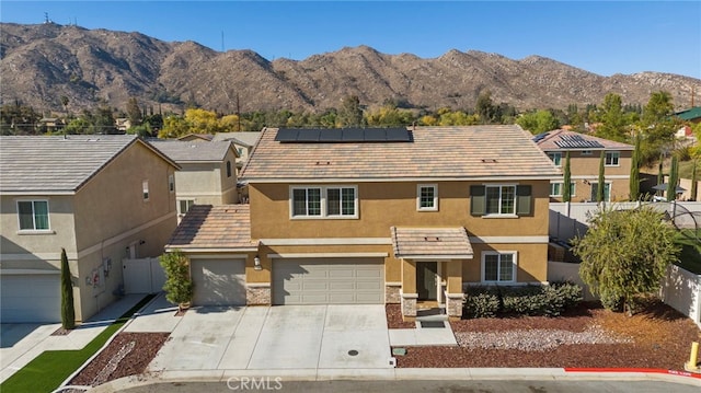 view of front of home featuring a garage, a mountain view, and solar panels