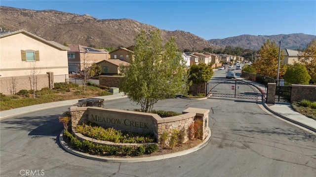 view of road with street lights, a mountain view, a gated entry, a residential view, and curbs