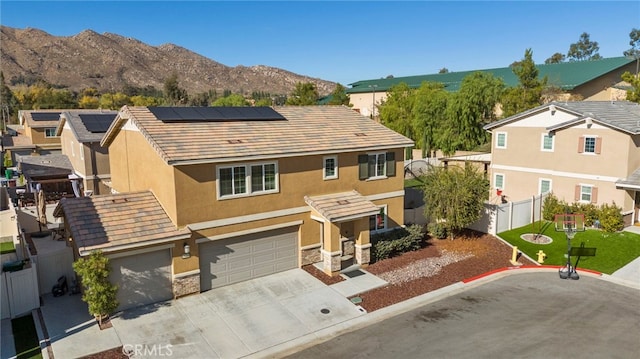 view of front of home with a front lawn, a garage, a mountain view, and solar panels