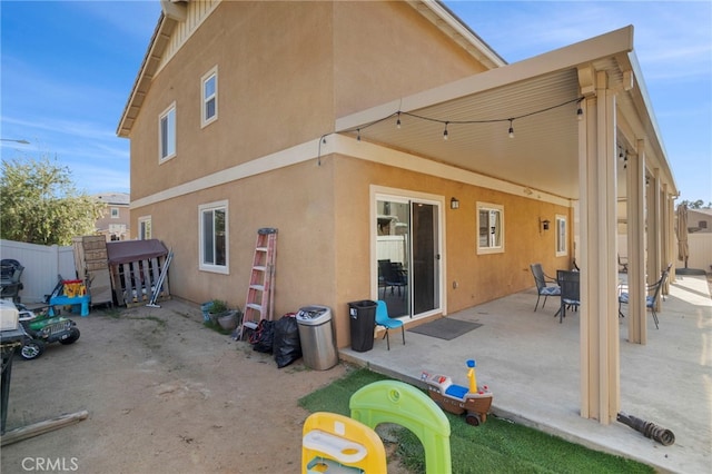 rear view of property featuring fence, a patio, and stucco siding