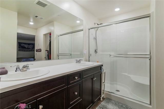 bathroom featuring a shower with shower door and vanity