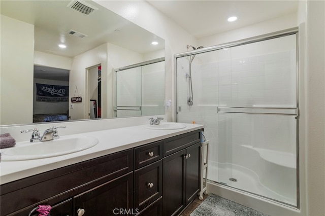 ensuite bathroom with double vanity, a sink, visible vents, and a shower stall