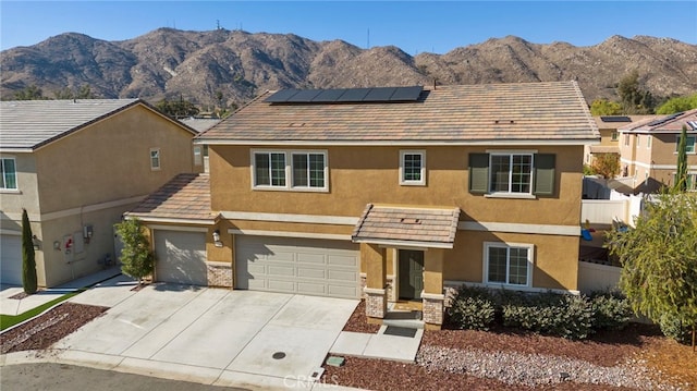 view of front of property with a garage, a mountain view, and solar panels