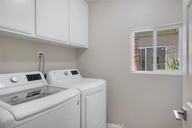 clothes washing area with washing machine and clothes dryer and cabinets