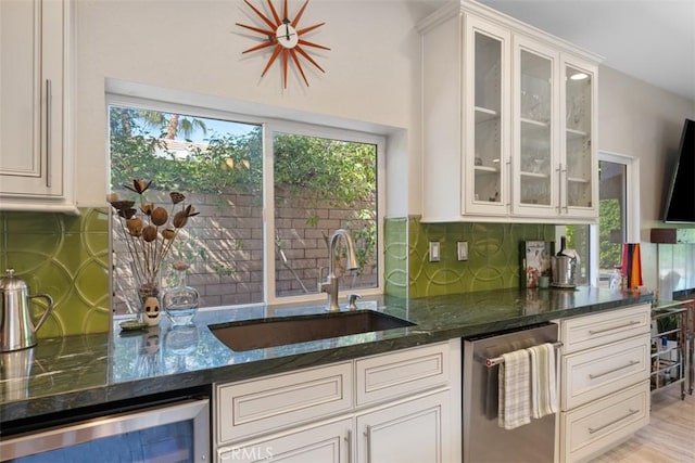 kitchen featuring dishwasher, white cabinetry, dark stone countertops, sink, and backsplash