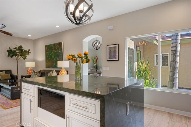 kitchen with white cabinetry, a wealth of natural light, a chandelier, and dark stone countertops