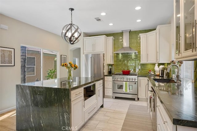 kitchen featuring white cabinets, wall chimney exhaust hood, high end appliances, and a kitchen island