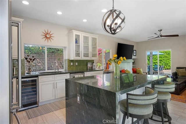 kitchen with sink, pendant lighting, white cabinets, and wine cooler