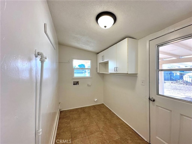 clothes washing area with cabinets, a textured ceiling, plenty of natural light, and hookup for a washing machine