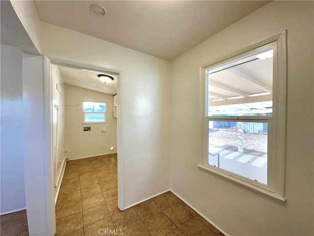 corridor with lofted ceiling and tile patterned flooring