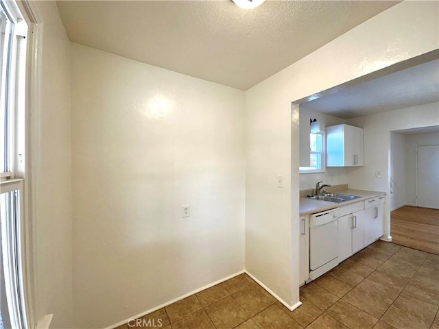 kitchen featuring white cabinets, dishwasher, sink, and a textured ceiling