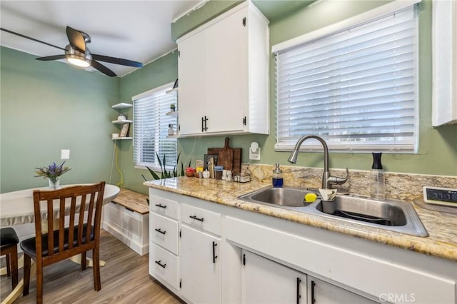 kitchen featuring ceiling fan, sink, white cabinetry, and light hardwood / wood-style flooring