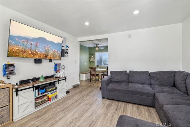 living room with ceiling fan and light hardwood / wood-style flooring