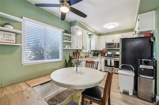 kitchen featuring appliances with stainless steel finishes, white cabinetry, sink, light wood-type flooring, and ceiling fan