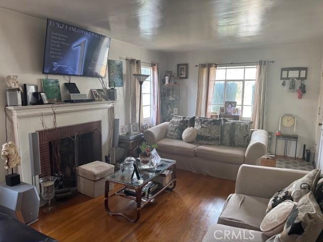 living room with a brick fireplace and hardwood / wood-style flooring