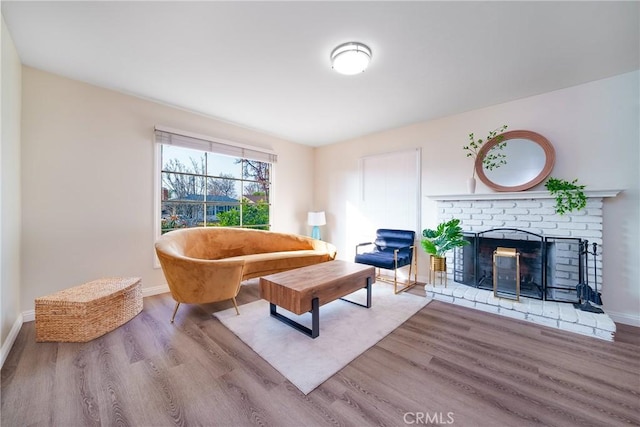 living room with a brick fireplace and light hardwood / wood-style flooring