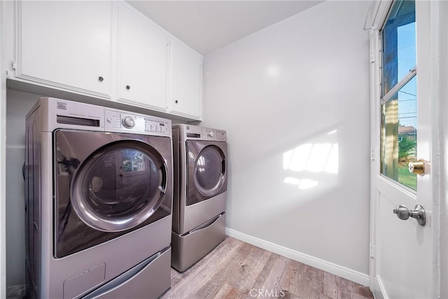 laundry room featuring cabinets, separate washer and dryer, and light hardwood / wood-style floors