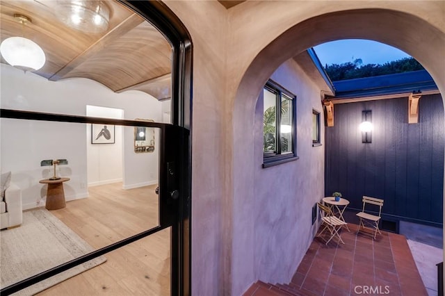 interior space featuring hardwood / wood-style flooring, brick ceiling, and lofted ceiling