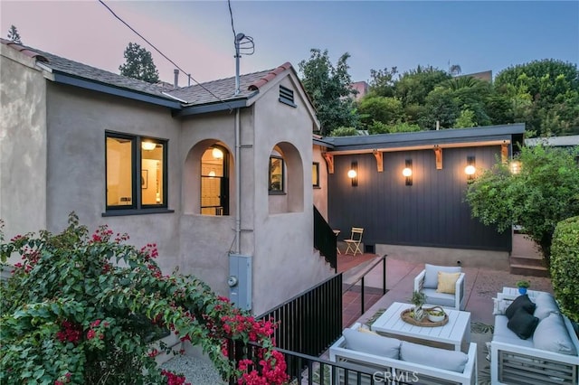 property exterior at dusk featuring an outdoor hangout area and a patio