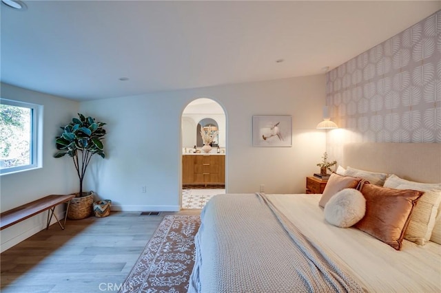 bedroom with wood-type flooring and connected bathroom