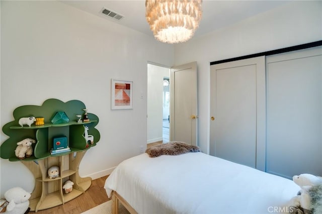 bedroom featuring hardwood / wood-style floors, a closet, and an inviting chandelier