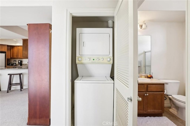 clothes washing area featuring light carpet, stacked washer and dryer, and sink