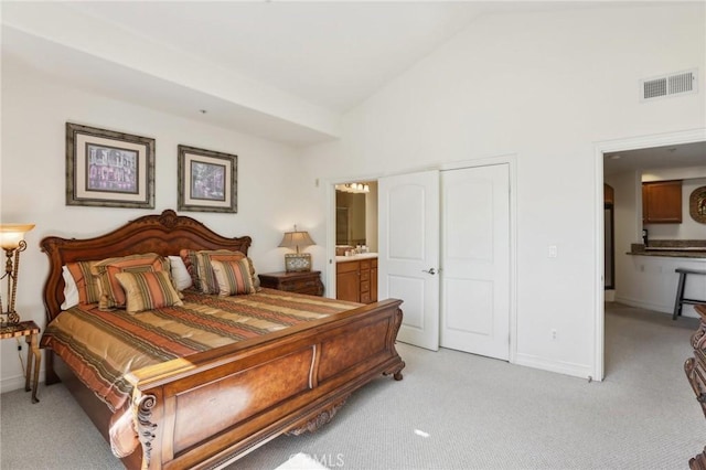 carpeted bedroom with high vaulted ceiling and ensuite bath