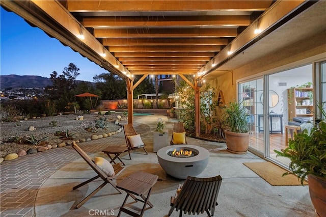 patio terrace at dusk featuring a mountain view and a fire pit