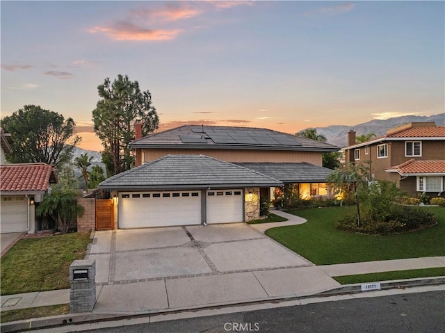 view of front of property with a mountain view, solar panels, a yard, and a garage