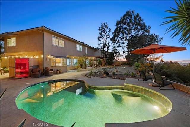 pool at dusk featuring a patio area