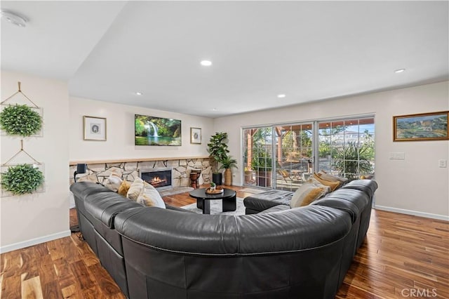 living room with wood-type flooring and a stone fireplace