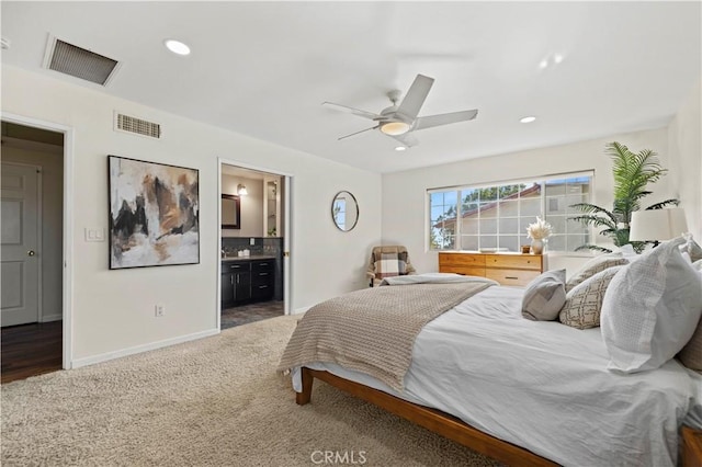 bedroom with ceiling fan, dark colored carpet, and ensuite bath