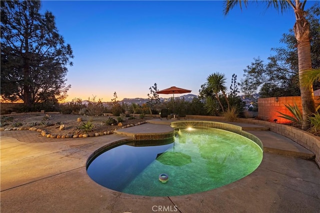 pool at dusk with a patio area