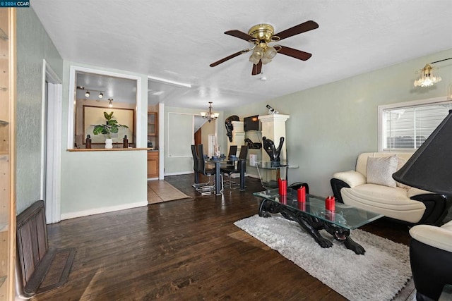 workout area featuring dark wood-type flooring and ceiling fan with notable chandelier