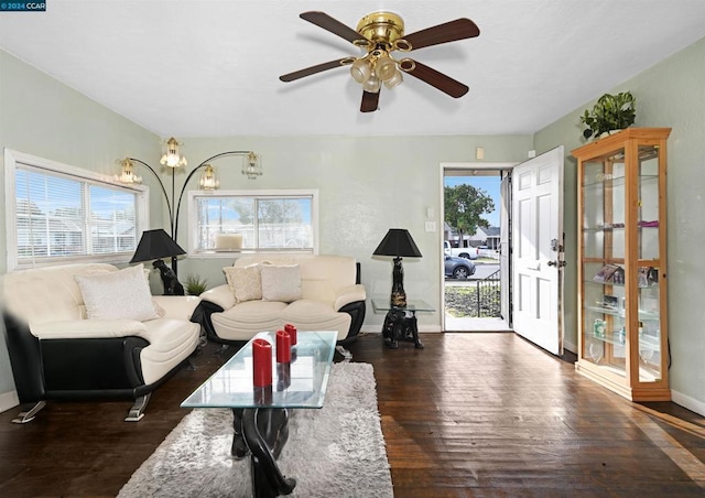 living room with ceiling fan with notable chandelier and dark hardwood / wood-style floors