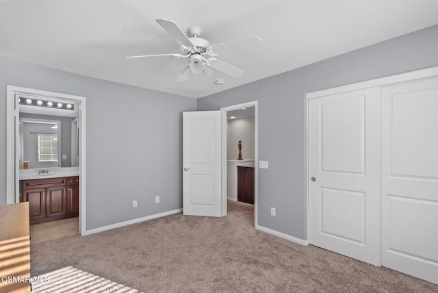 unfurnished bedroom with ceiling fan, ensuite bath, a closet, light colored carpet, and sink