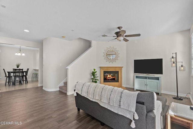 living room featuring ceiling fan with notable chandelier and hardwood / wood-style floors