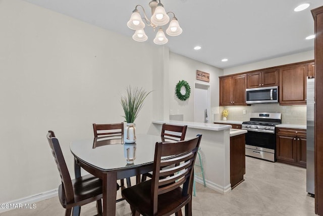 kitchen with decorative light fixtures, stainless steel appliances, decorative backsplash, kitchen peninsula, and a chandelier