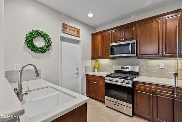 kitchen with light tile patterned flooring, stainless steel appliances, backsplash, and sink