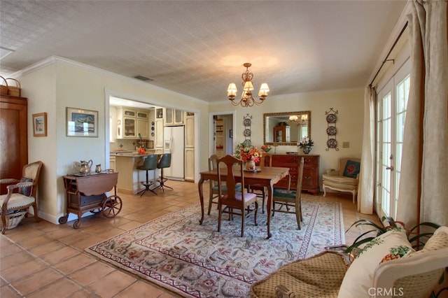 dining space featuring a textured ceiling, ornamental molding, a notable chandelier, and light tile patterned flooring