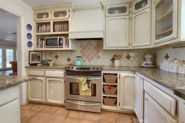 kitchen with custom exhaust hood, cream cabinetry, tasteful backsplash, and stainless steel appliances