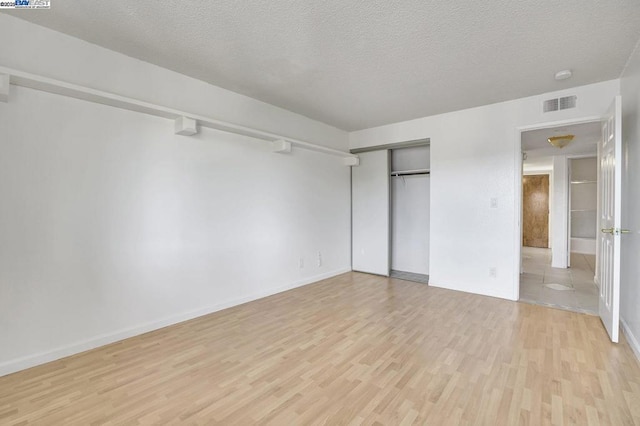 unfurnished bedroom featuring a textured ceiling, a closet, and light wood-type flooring