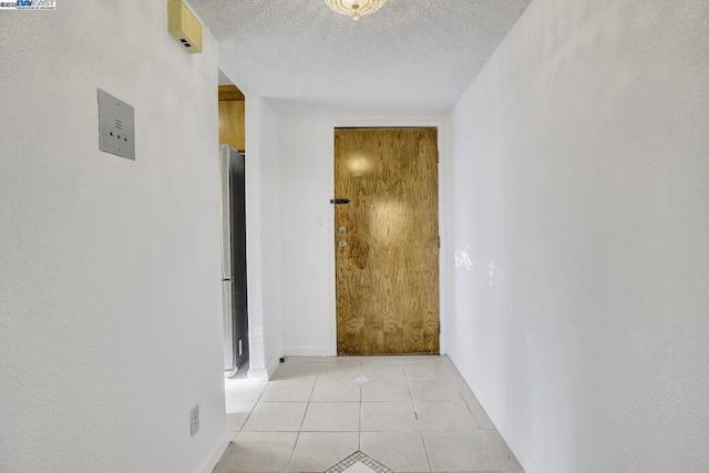 hall featuring a textured ceiling and light tile patterned flooring