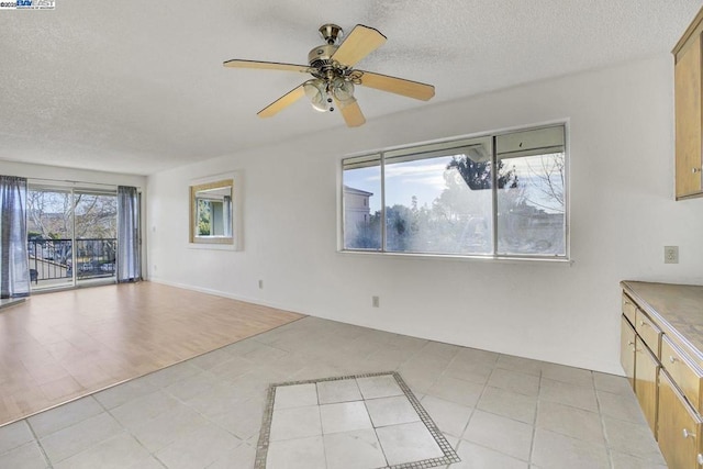 interior space with ceiling fan, light tile patterned floors, and a textured ceiling